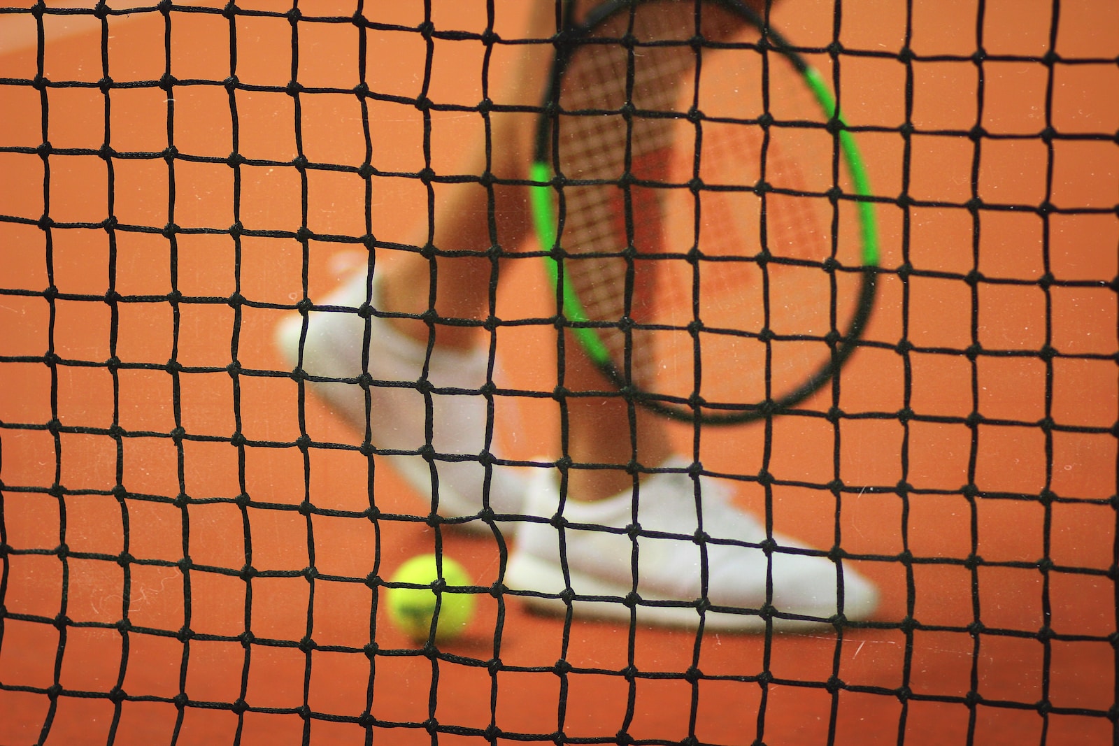 Joueur de tennis avec sa raquette et une balle devant le filet